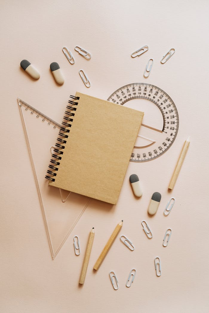 An organized flat lay of school supplies including a notebook, pencils, and paper clips.